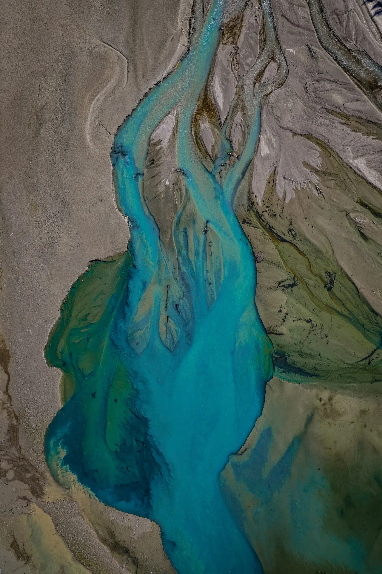 An aerial view of turquoise river streams converging into one delta