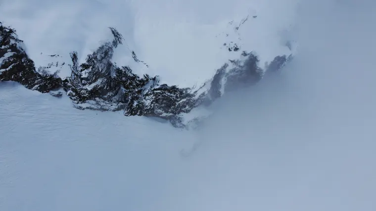 A clean aerial view of snow-covered ridges fading into fog