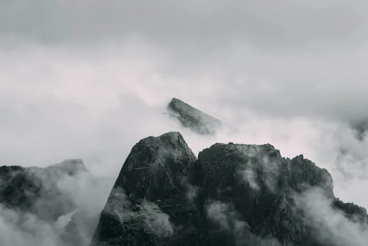 Dark jagged peaks breaking through layers of cloud