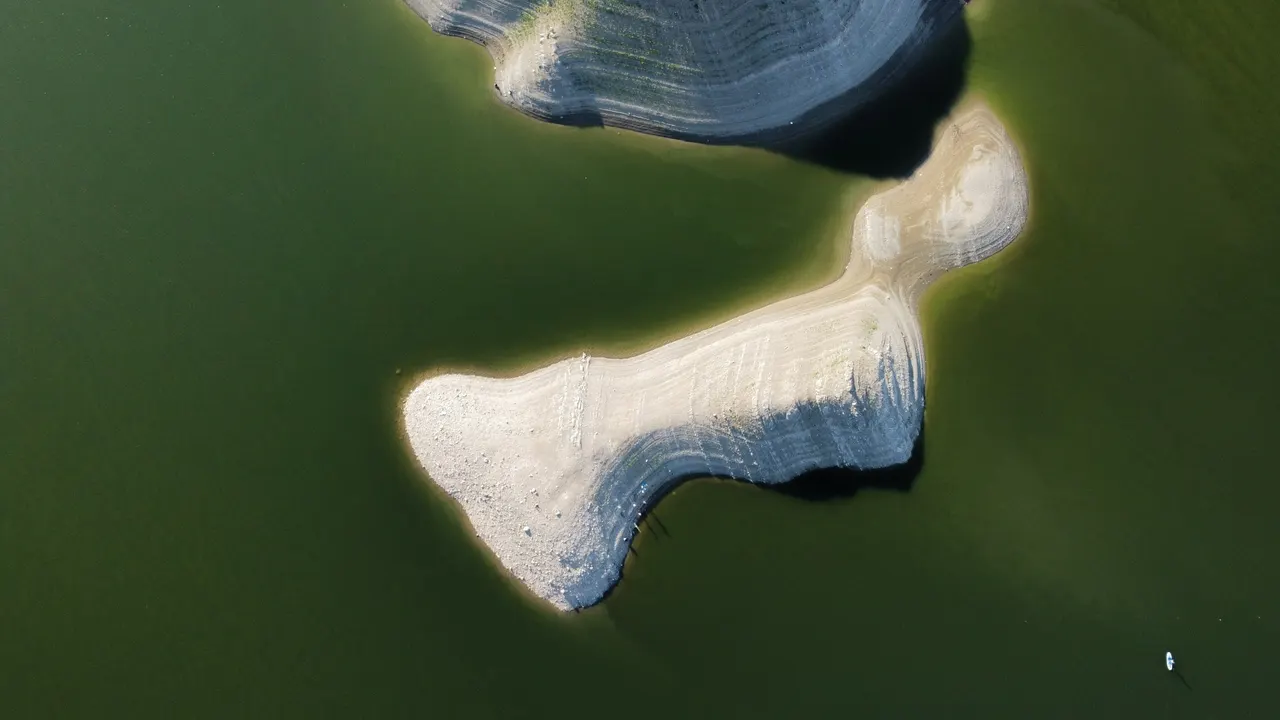 An aerial view of solid sandbars set in calm, deep green water