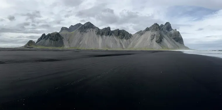 A sweeping mountain range rising above a black sand plain