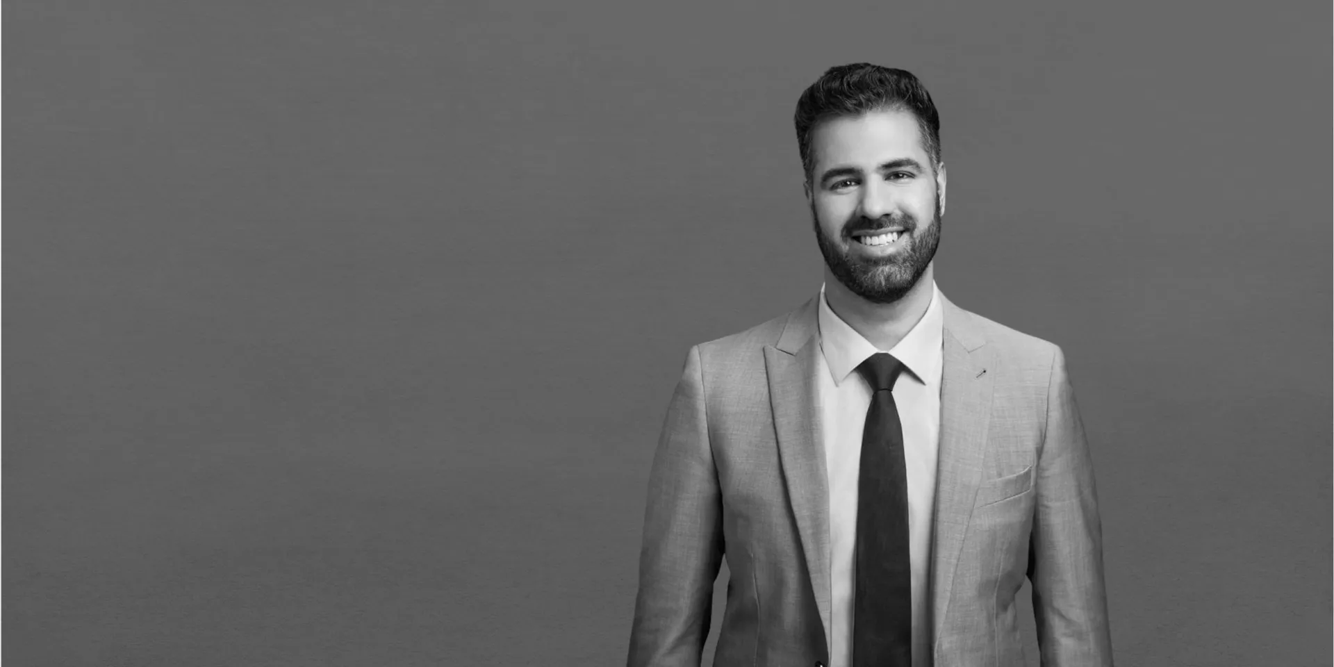 Stratford Pacific principal in a tailored light suit against a grey studio backdrop